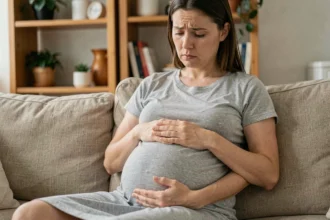 Femme enceinte stressée assise sur un canapé, les mains sur le ventre, illustrant les effets du stress pendant la grossesse